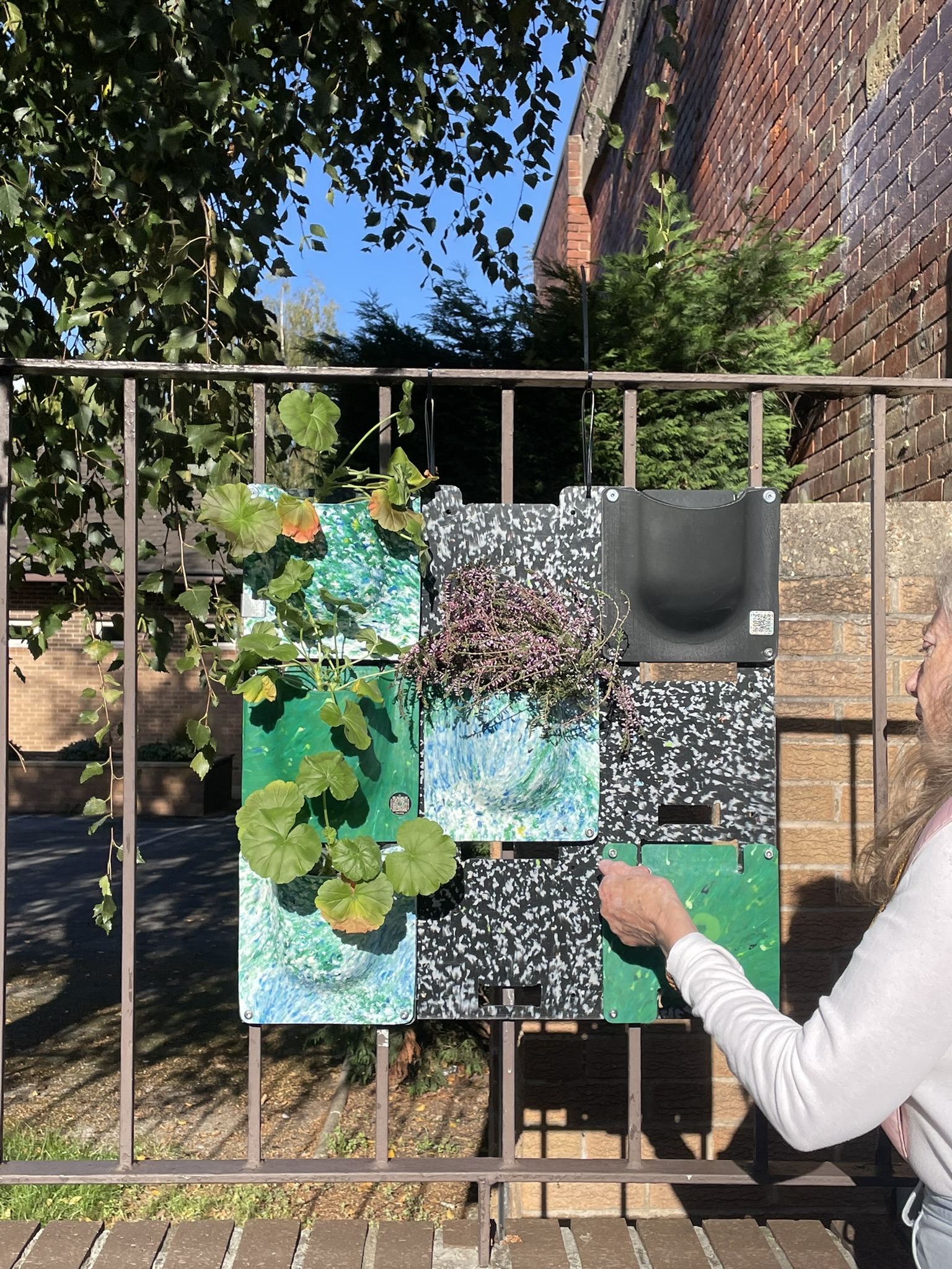 Marbled recycled-plastic planter tiles mounted on an urban brick wall